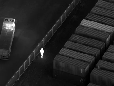 Thermal view: one person walking inside the fence glows white